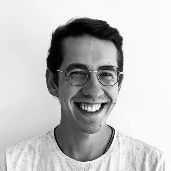 Portrait en noir et blanc de Raphaël, souriant, avec des lunettes.